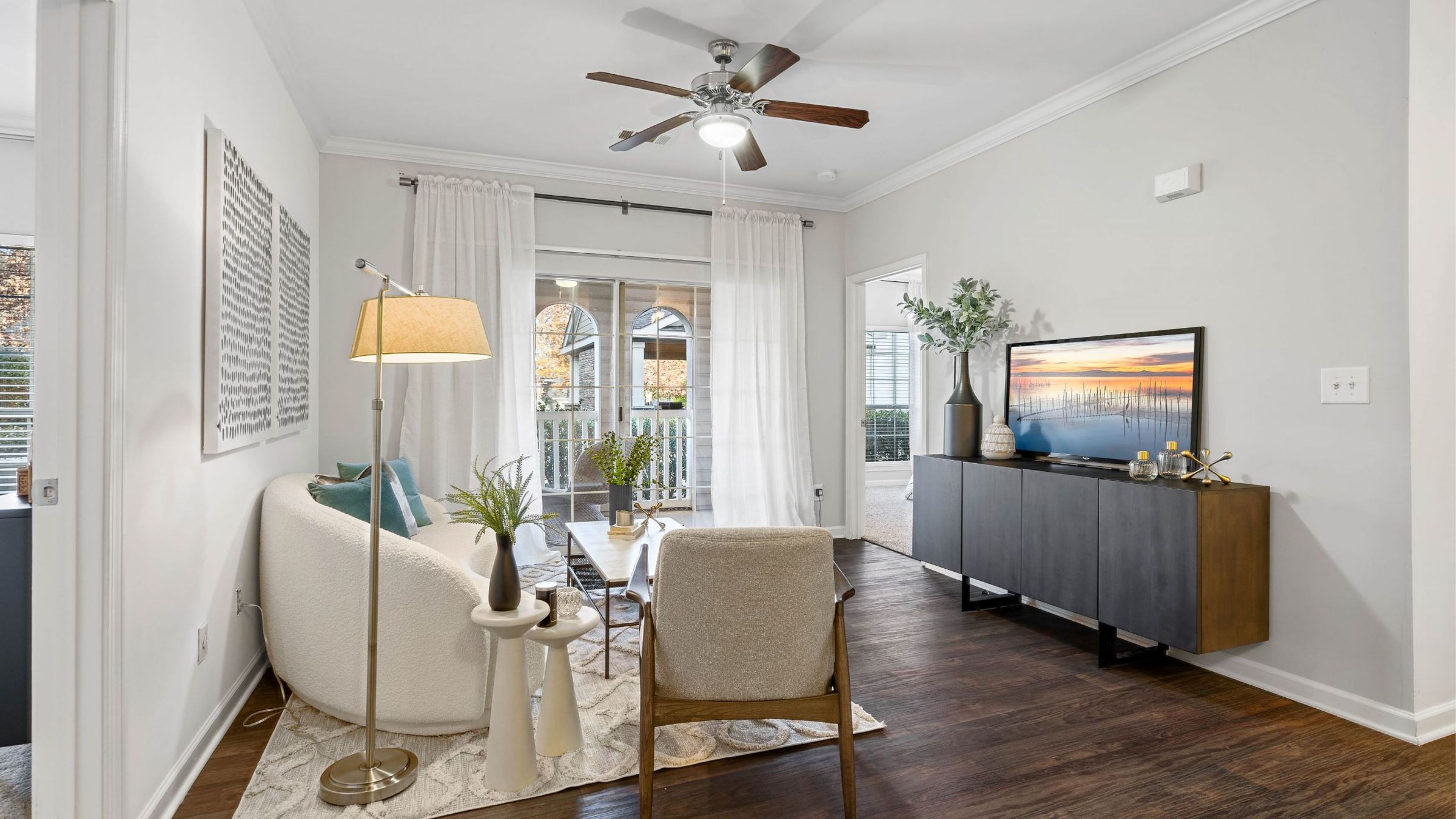Hawthorne at the Carlyle spacious apartment living area with hardwood floors and large glass doors to an outdoor patio.